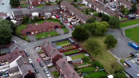 Aerial-view-above-British-neighbourhood-small-town-residential-suburban-property-gardens-and-town-streets-left-birdseye-pan