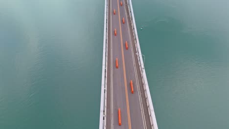 vital freight link in tacloban reduced to single lane during major 2-year repairs - top down view of road, changing to landscape bridge with mountains