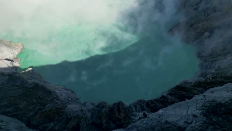 top view of the blue acid lake in ijen volcano with smoke in the air - banjuwangi - east java, indonesia