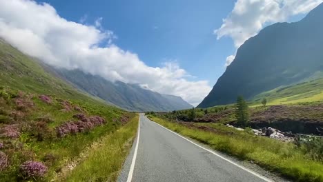 a driving shot down a road through the scottish highlands on a bright summers day