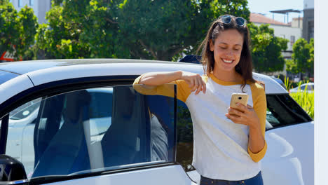 mujer usando teléfono móvil cerca de su coche 4k