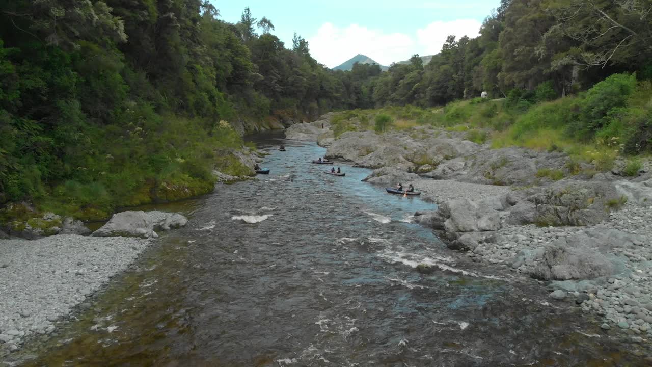 la gente rema en kayak por el rápido con rocas en el hermoso y prístino río azul claro pelours, nueva zelanda - drone aéreo