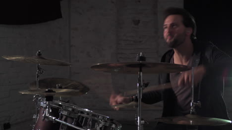 a close scene of a young european man playing on his favorite drumset in a dark room