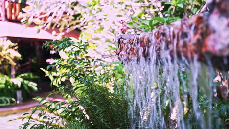 Water-stream-falling-from-roughly-carved-stone-slab-in-garden