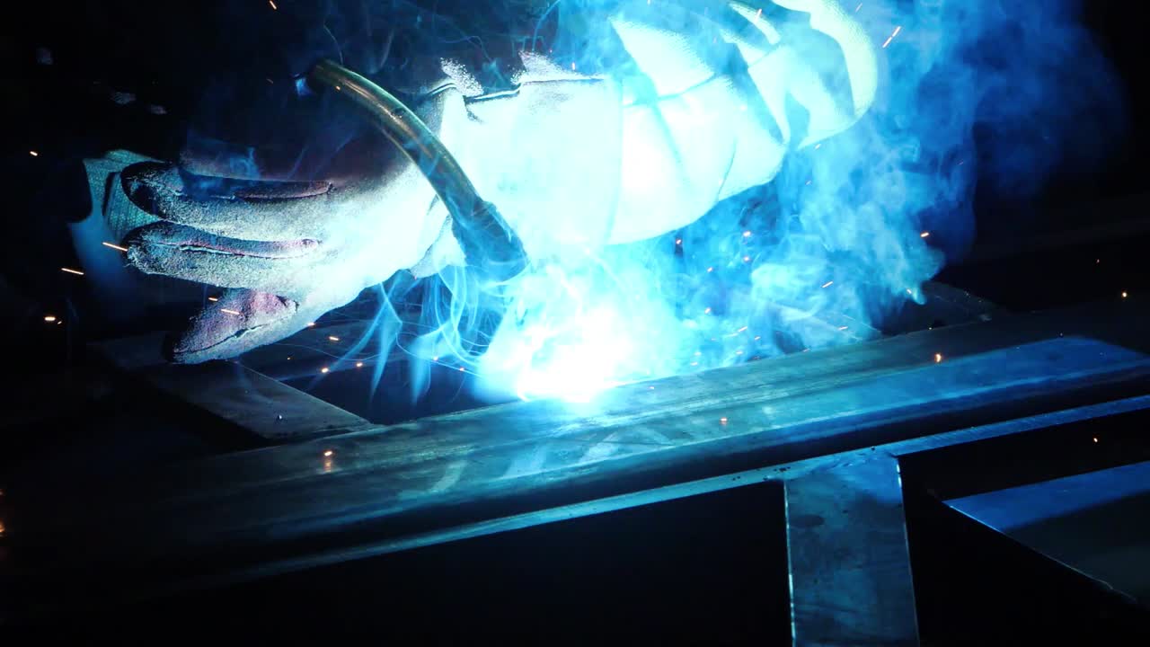 Professional welder making welding work on metal in darkness. Repair in workshop