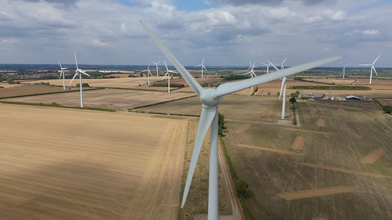 Drone view of modern wind turbines in golden countryside fields near Burton Latimer England with clear skies and open rural scenery