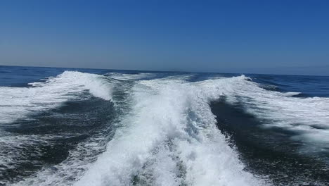 wake of water seen from behind of fast moving motor boat in a clear sky day,blue sea , water surface