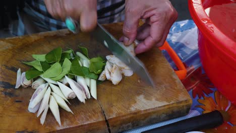 woman using a dull knife to cut vegetables on a wooden cutting board