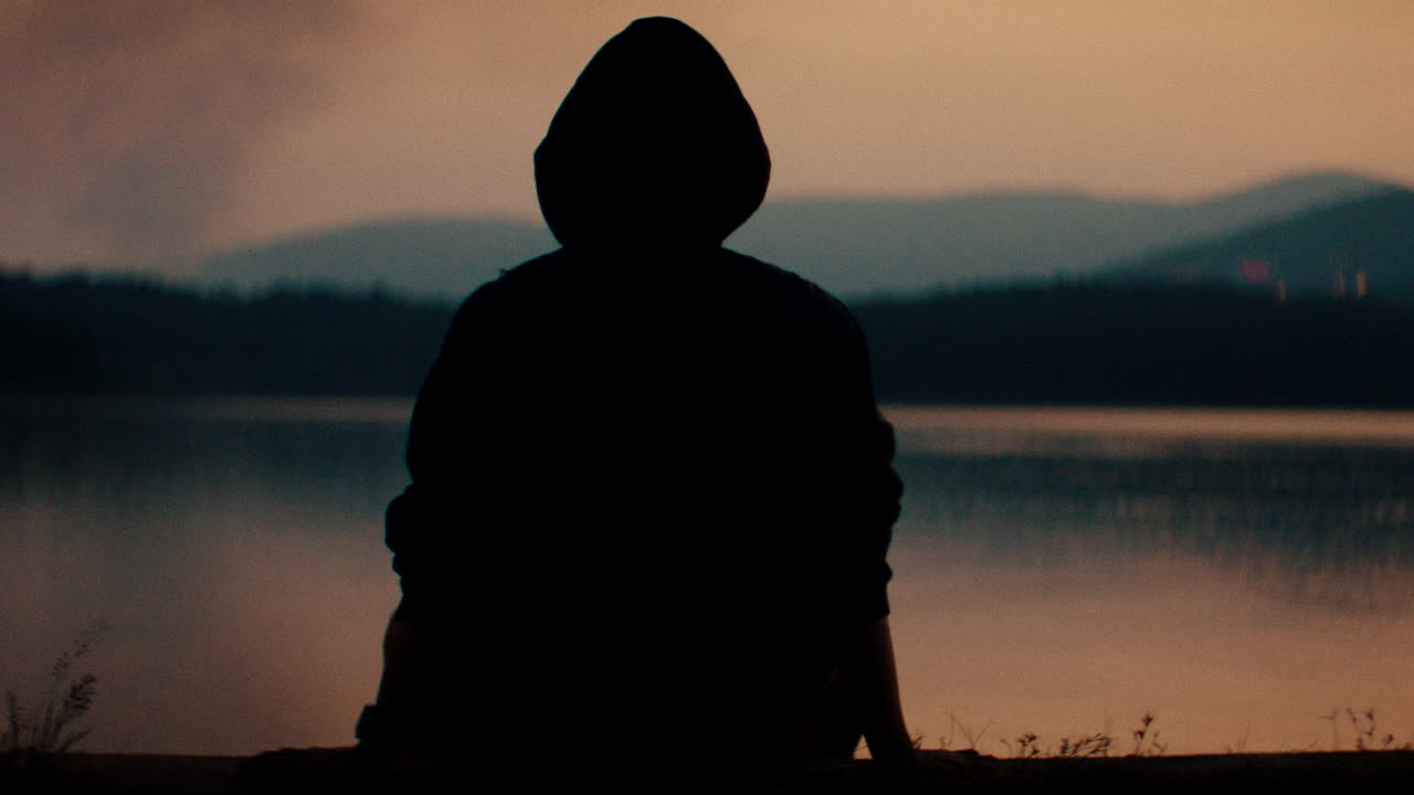 Person Silhouetted by a Lake at Sunset