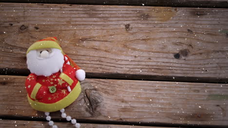 video composition with falling snow over desk with  santa doll