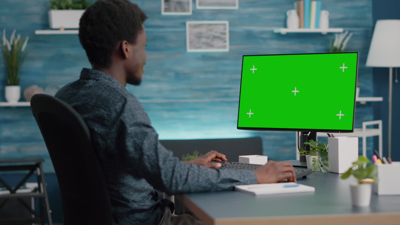African american man using and typing on mockup computer with green screen