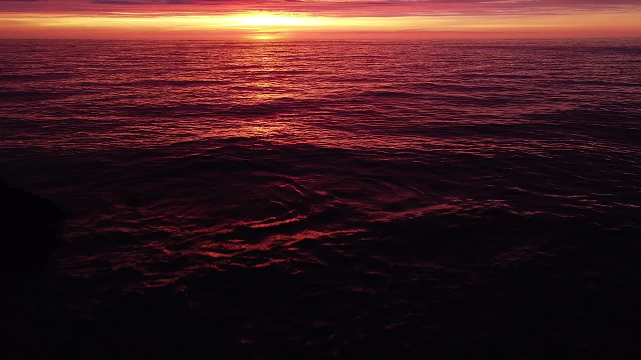 Wunderschöner, lebendiger, kontrastreicher, pink-violetter Sonnenuntergang aus der Luft über der Ostsee, Ruinen der Küstenbefestigungen aus Beton des Kriegshafens Karosta bei Liepāja, Weitwinkel-Drohnenaufnahme, vorwärtsfliegend, Kamera schwenkt nach oben