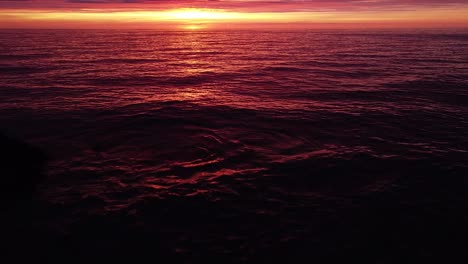 hermosa antena vibrante alto contraste rosa púrpura puesta de sol sobre el mar báltico, puerto de guerra de karosta ruinas de fortificación de la costa de hormigón en liepaja, disparo de drones de gran angular avanzando, inclinación de la cámara hacia arriba
