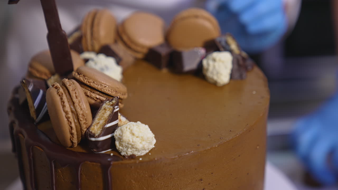 Amazing decorated chocolate cake rotating at the stand. Beautiful tasty dessert production at food factory. Close up.