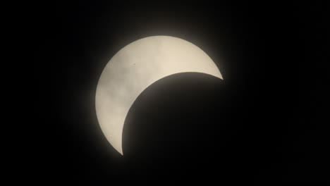 solar eclipse in motion with passing clouds