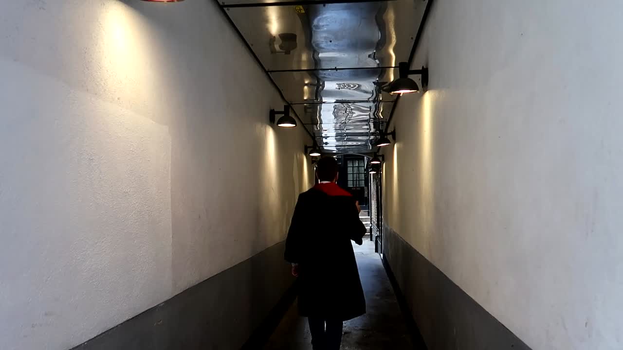 un hombre vestido como harry potter saca una varita mágica y camina por el callejón con ella apuntando hacia arriba.
