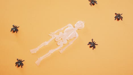 multiple skeleton and spider toys with copy space against orange background