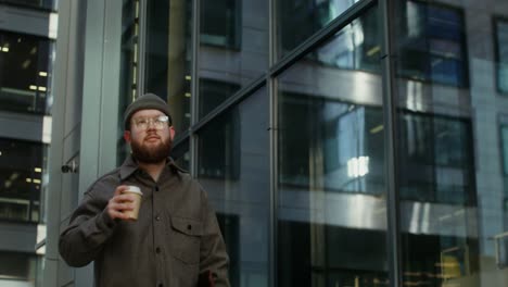 man walking down city street with coffee