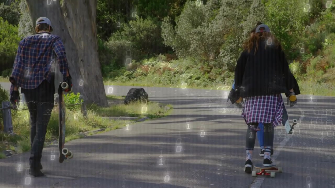 Donna che si spinge, prendendo velocità, mentre due amici camminano con le tavole lungo una strada asfaltata per svago