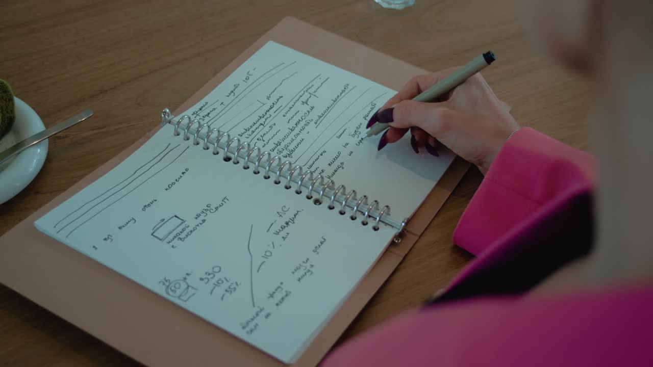Woman Taking Notes in a Cafe