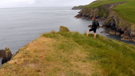 man standing on cliff mountain with his hand on hip 4k