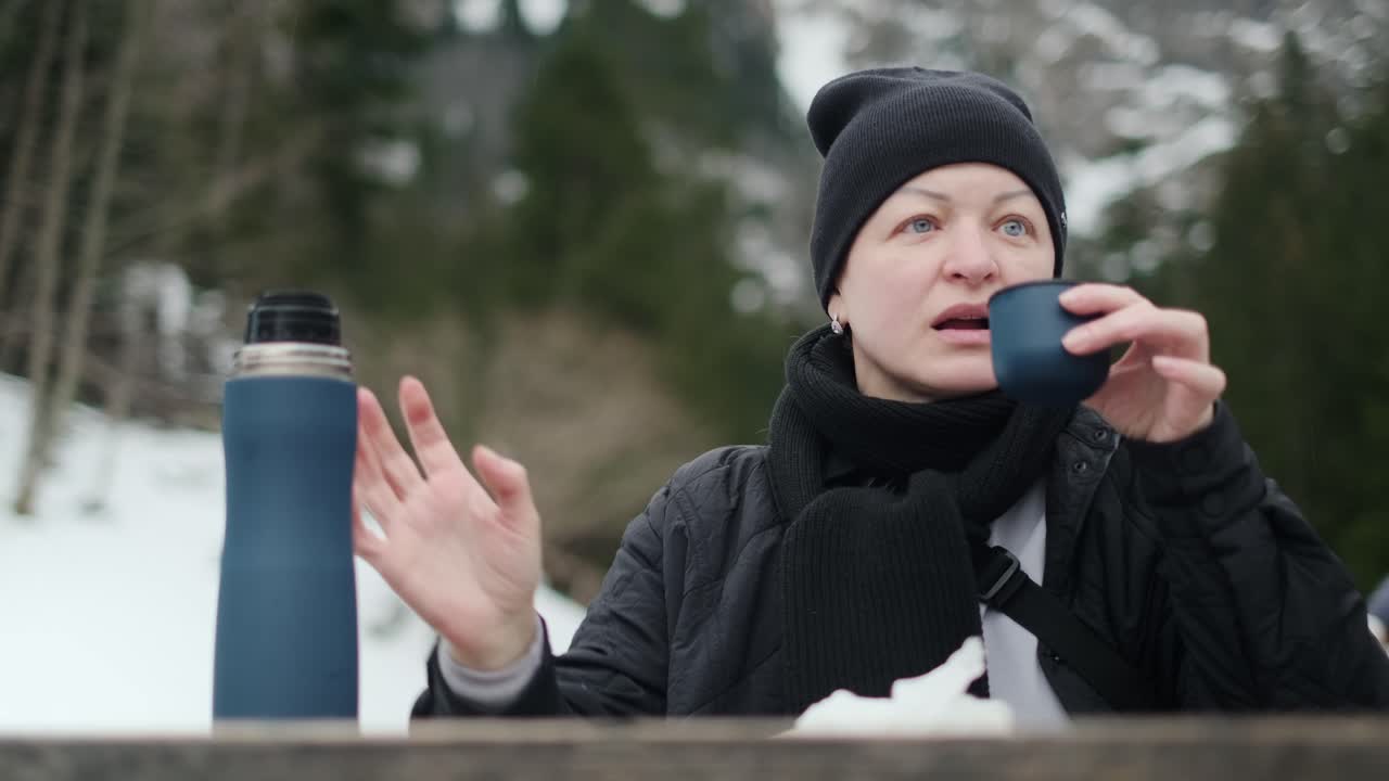 Woman enjoying a hot drink in snowy mountains