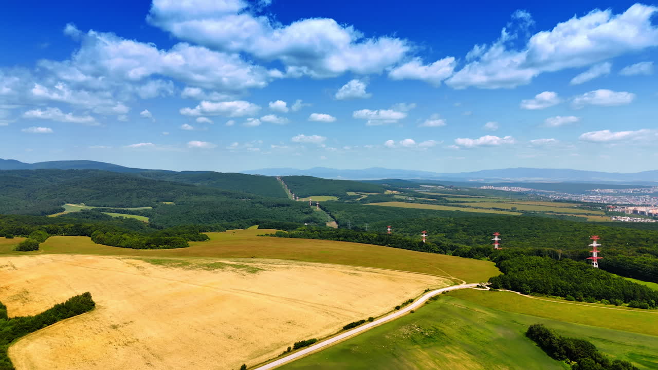 Green fields, blue skies in Europe. Expansive fields stretch across the landscape under a bright blue sky dotted with clouds