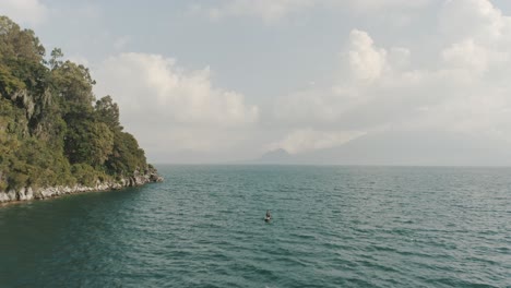 drone aerial shot rotating around beautiful forest on the bay of lake atitlan, guatemala