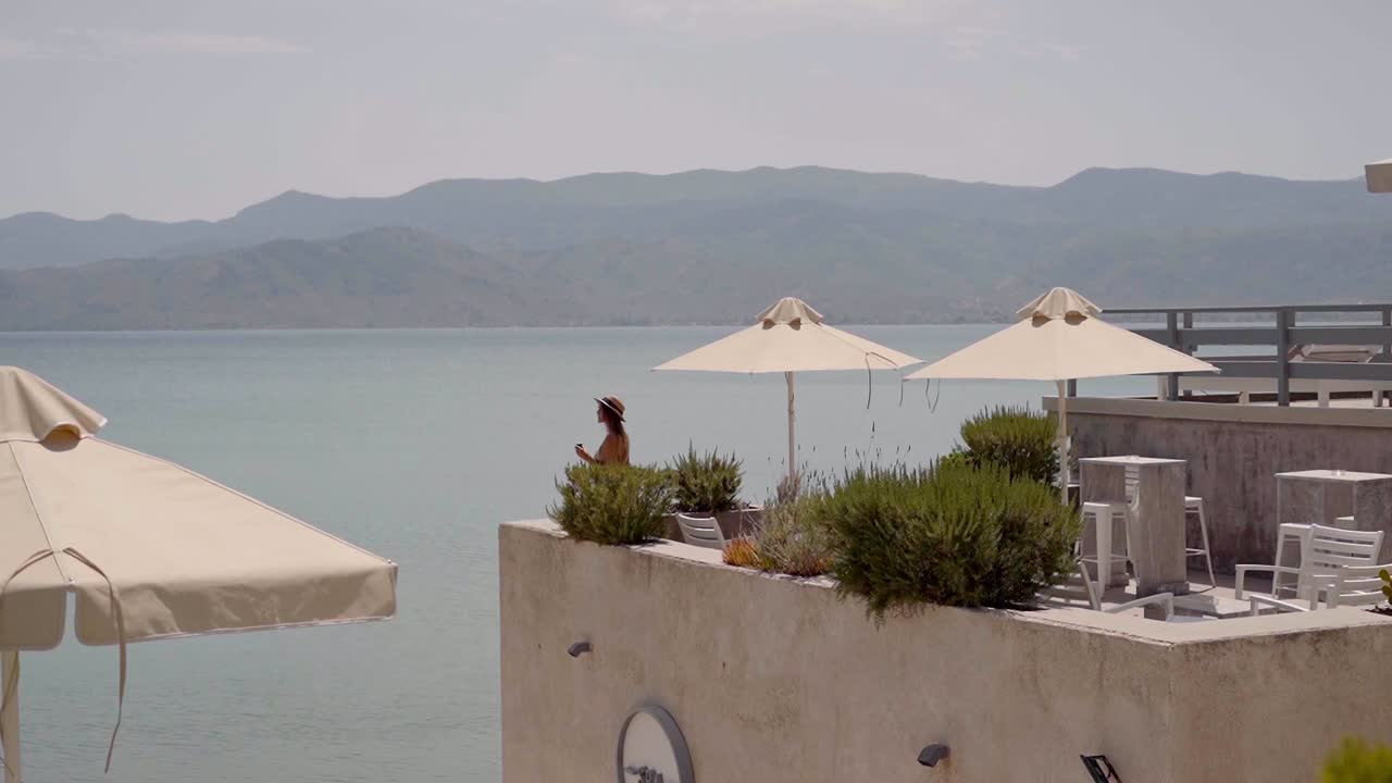 Woman tourist enjoying overlooking ocean bay in Lesvos Island, Thermi on Yera, Revealing shot