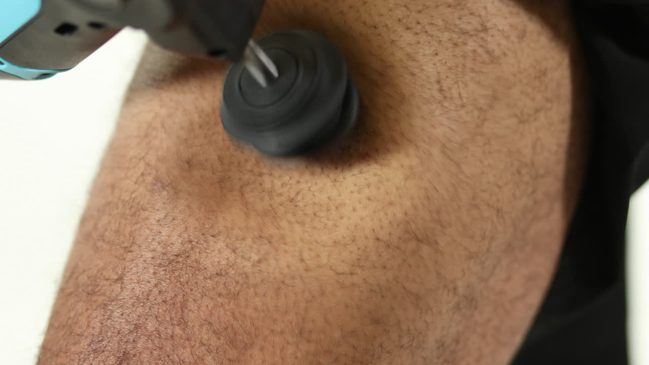 atleta que usa una pistola de terapia de percusión en la pierna para aliviar, recuperar y activar los músculos