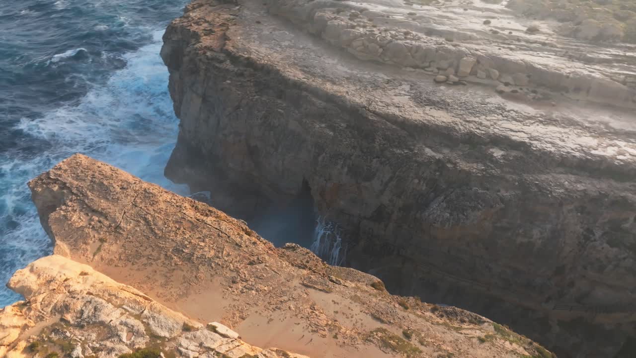 Turbulent Sea With Waves Crashing Through Limestone Cliffs Of Azure Window In Gozo, Malta. orbiting drone shot