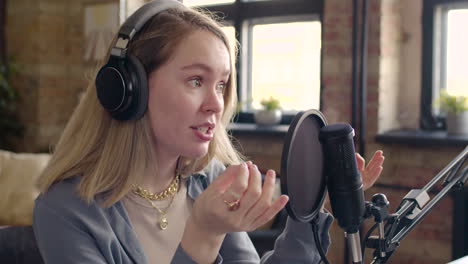 vista de cerca de una mujer con auriculares hablando por un micrófono grabando un podcast