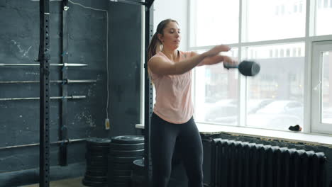 woman performing kettlebell swings in a gym