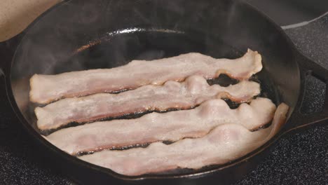 cast iron pan on stove frying bacon cooking hot grease