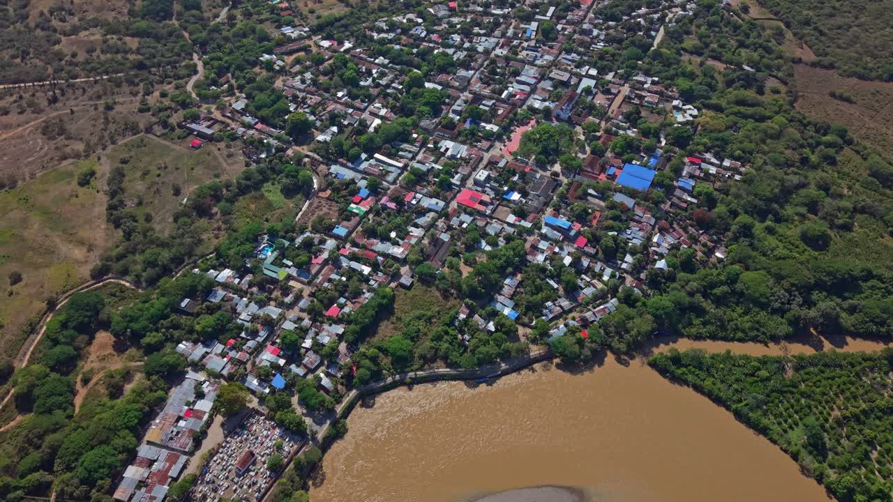 Drone approaches Villavieja, gliding over the adjacent river, capturing the town's layout, flowing waters, and surrounding landscape, giving a smooth, cinematic aerial perspective of the area
