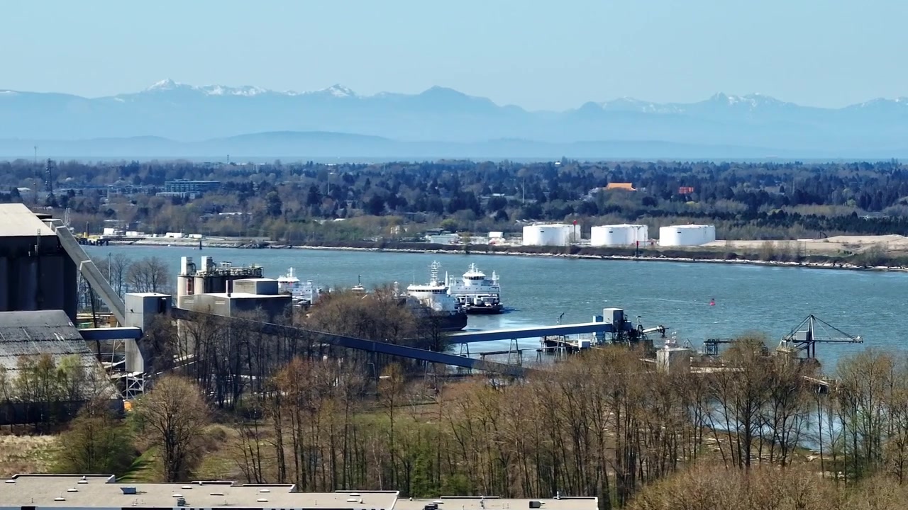 Una vista panoramica delle operazioni di spedizione Seaspan e del terminal dei traghetti commerciale e industriale lungo il fiume Fraser a Delta, Richmond, Columbia Britannica, Canada - Ripresa con drone in orbita.