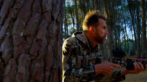 man aiming with compound bow in the forest 4k