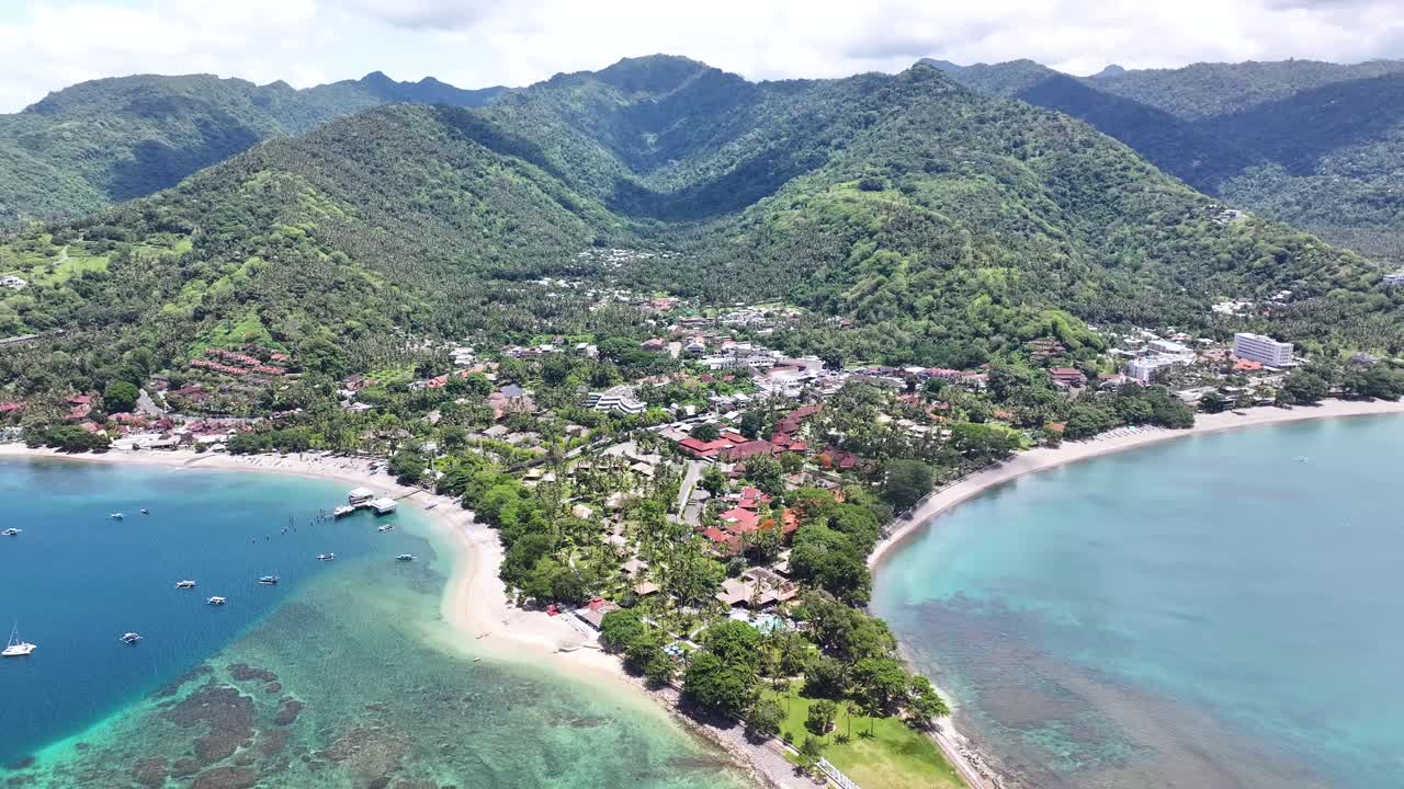la ciudad de senggigi junto al mar azul con montañas verdes y playa tropical durante el verano en indonesia.