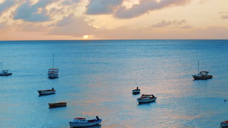 beautiful golden sunset over the ocean in curacao, caribbean, as local fishing boats float on the calm blue water