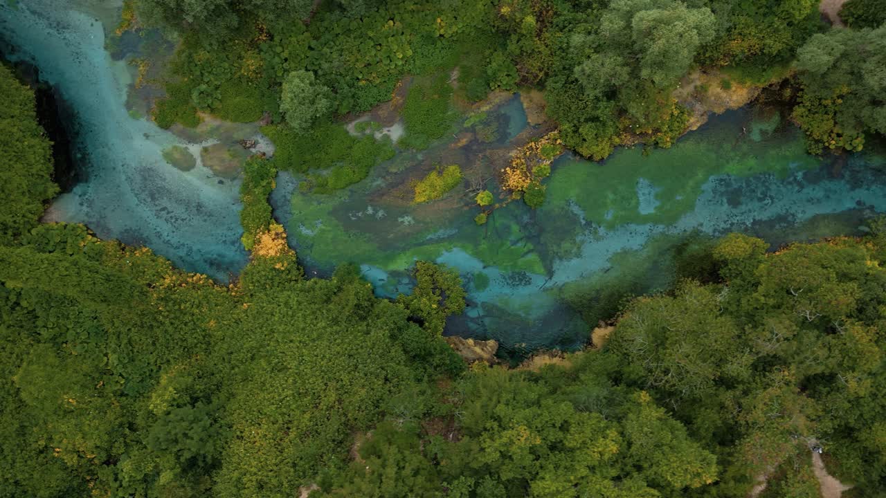 Aerial of Syri i Kaltër, the famous Blue Eye of Albania, with deep blue water and natural green vegetation.