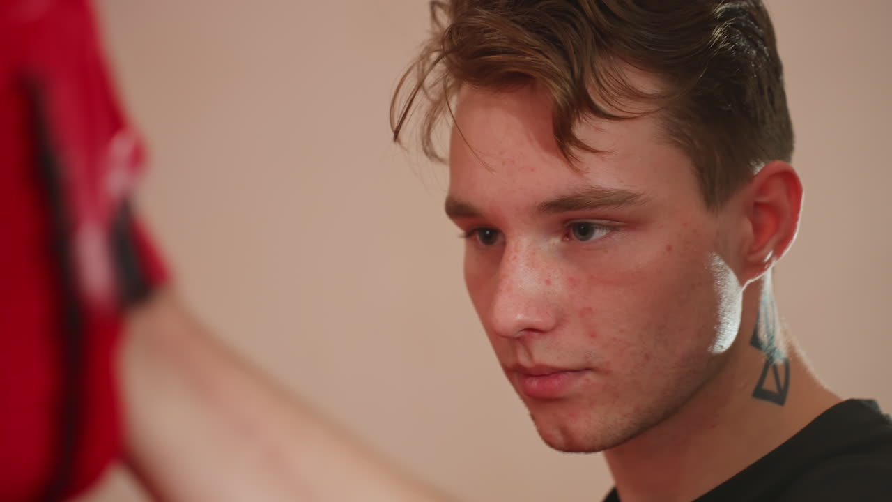 MMA fighter with focused expression holds red punching mitt during intense training session inside gym, demonstrating concentration, discipline, and precision while preparing for combat