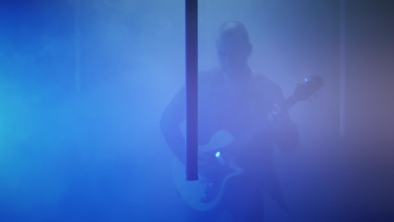 연기 속에서 기타를 연주하는 남자