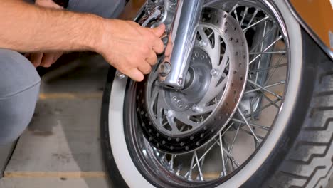 person performing maintenance on a motorcycle front wheel and disc brake