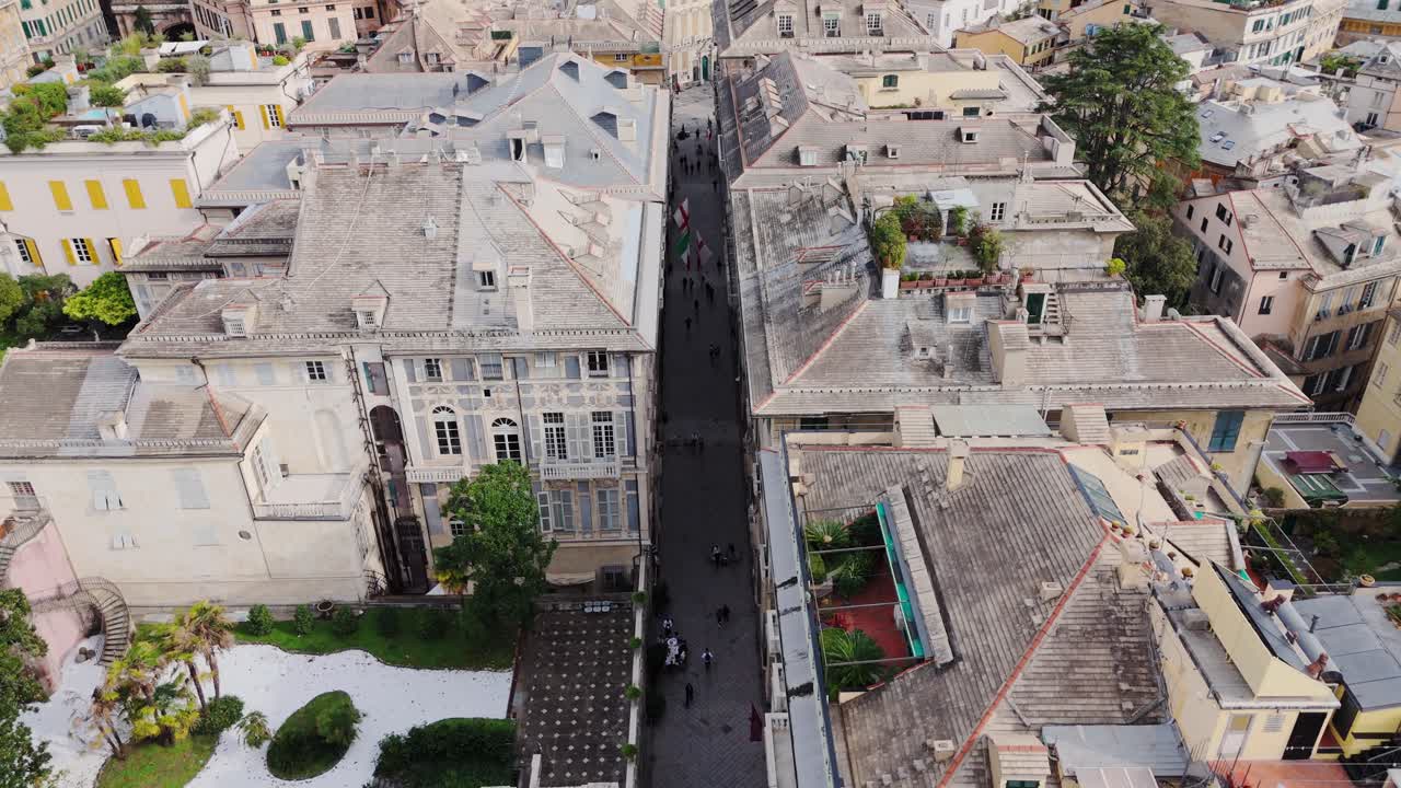 Genoa's historic center with ancient buildings and tourists walking down narrow streets, aerial view