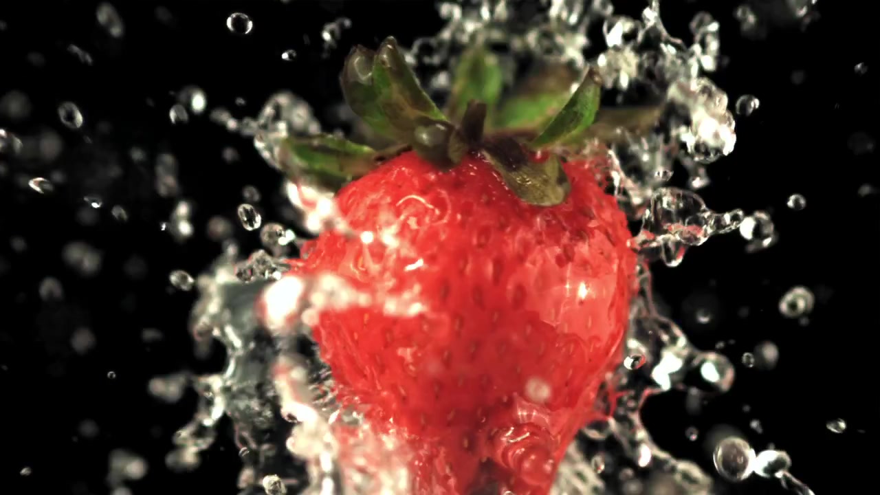 Acqua che schizza su una fragola rossa fresca al rallentatore