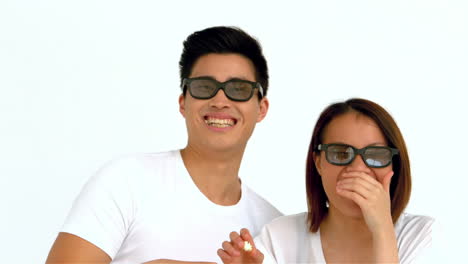 laughing asian couple eating popcorn and wearing movie glasses