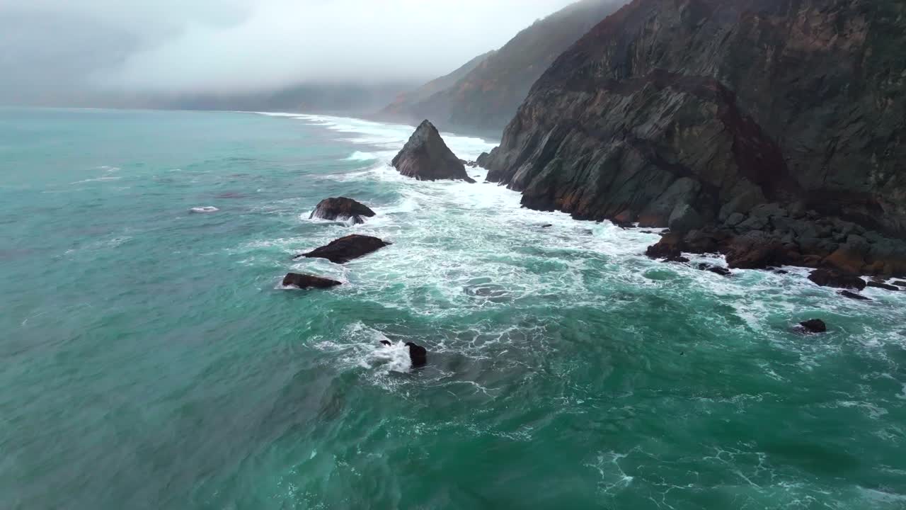 Rugged dramatic untouched coastline aerial drone California surf waves crashing boulder rocks USAL Beach campground cloud layer mist rain fog PNW Lost Coast Trail morning nature landscape forwards