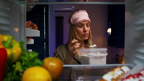 mujer comiendo helado del refrigerador por la noche