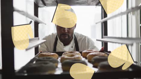 animation of oven glove icons over african american male baker preparing donuts