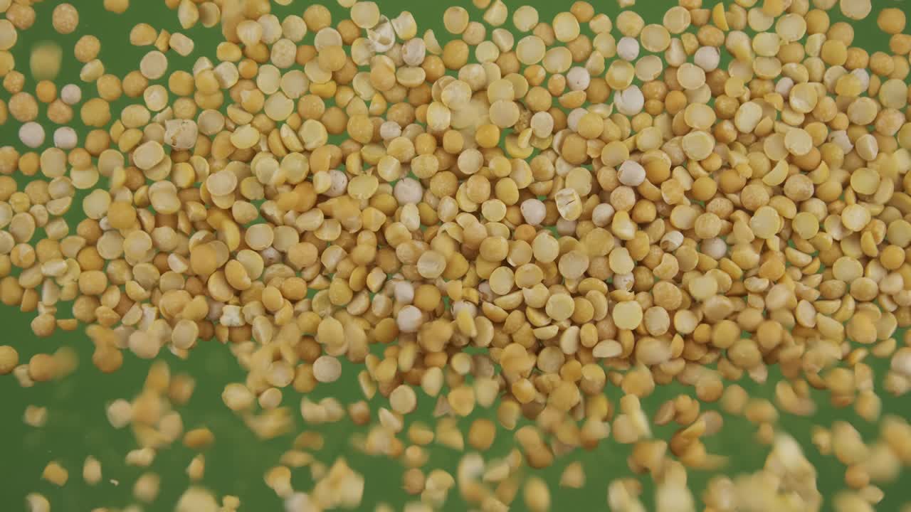 Top view of falling down peas grains. The seeds fall and fill the green screen. Grain background